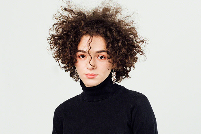 in studio portrait, beautiful young girl with curly unruly hair, simple and classic